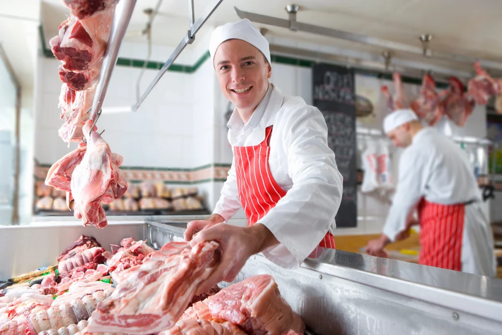 a young butcher smiling and holding meat near the 2026 01 11 08 41 41 utc Kopie